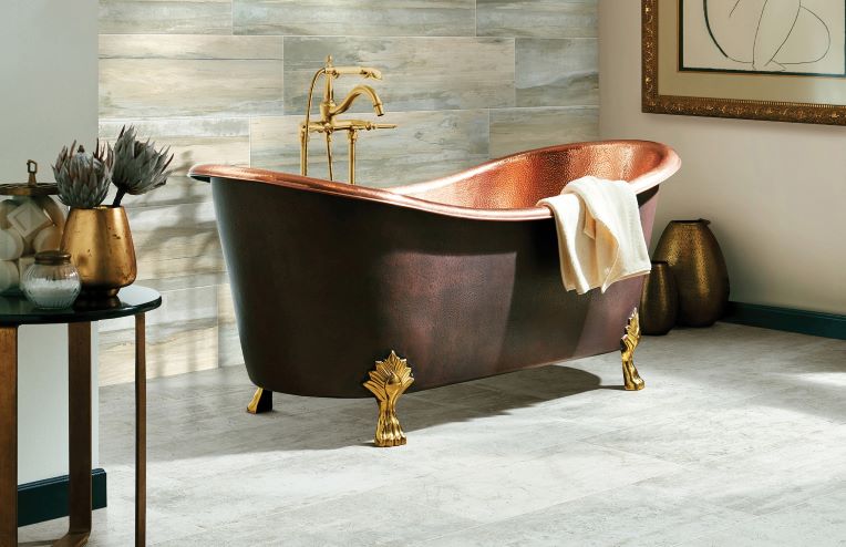 large neutral grey tile flooring in a stylish bathroom with a copper tub